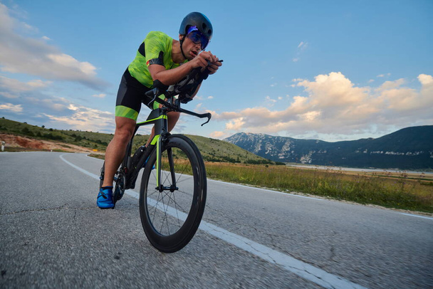 triathlon athlete riding professional racing bike at workout on curvy country road - Фото, зображення