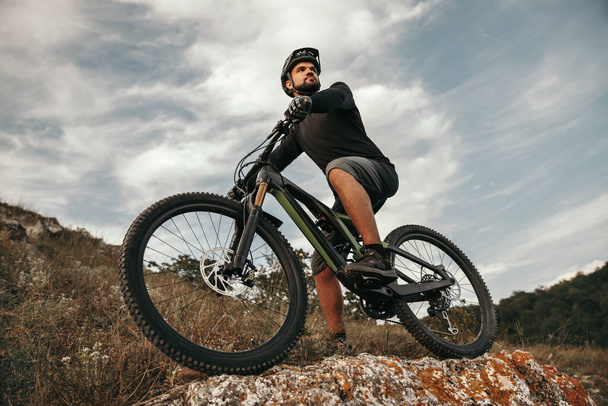 Male cyclist riding bike in mountains - Foto, imagen