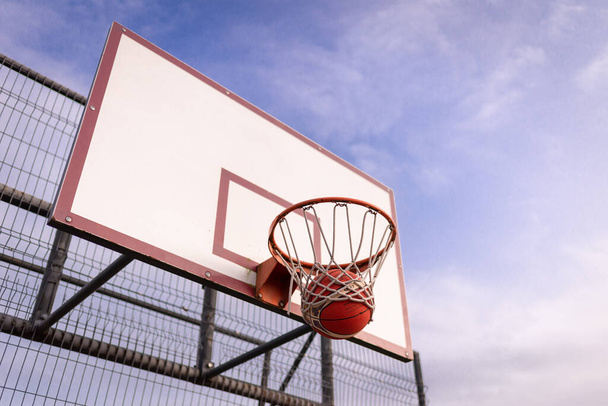 バスケットボールホワイトオールドボード青い曇天に対するバスケットフープ. - 写真・画像