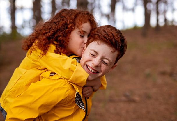 Redhead girl hugging and kissing brother - Фото, зображення