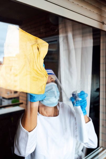 A takarítószemélyzet fertőtleníti a házat a vírus ellen, átlátszó védőmaszkot visel - Fotó, kép
