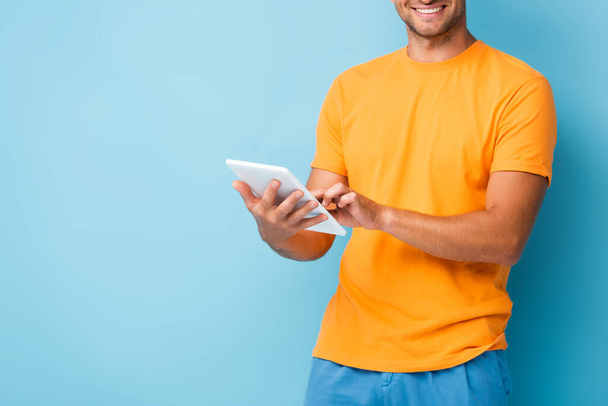 cropped view of happy man in t-shirt using digital tablet on blue - Fotoğraf, Görsel