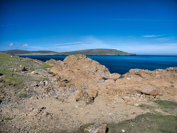 Rocha serpentina costeira na Keen of Hamar Nature Reserve, perto de Baltasound, na ilha de Unst, em Shetland, Reino Unido. A cúpula branca da cabeça do radar remoto RAF Saxa Vord pode ser vista à distância. - Foto, Imagem
