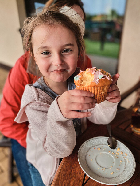 Girl enjoying eating sweet tasty cupcake that you she made herself at home - Photo, image