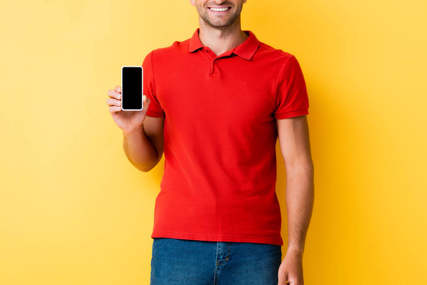 Ausgeschnittene Ansicht eines Mannes mit Smartphone und leerem Bildschirm auf gelb - Foto, Bild