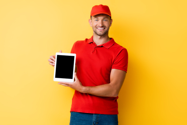 happy delivery man in red cap holding digital tablet with blank screen on yellow - Φωτογραφία, εικόνα