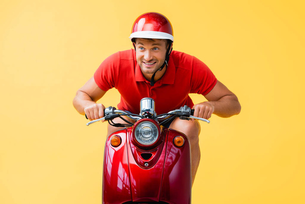 hombre feliz en casco de montar scooter rojo aislado en amarillo - Foto, Imagen