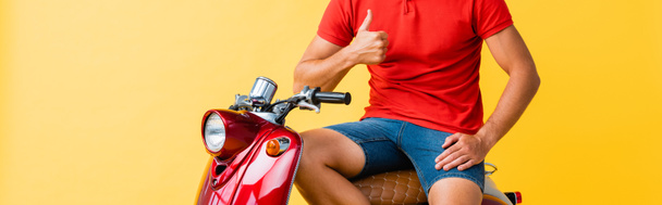 cropped view of man sitting on red scooter and showing thumb up on yellow - Foto, immagini