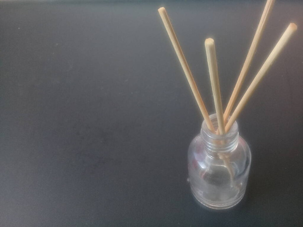 Primer plano de palos de incienso en recipiente de vidrio contra fondo gris. Palos de aroma tradicionales para el aire refrescante de la fragancia - Foto, imagen