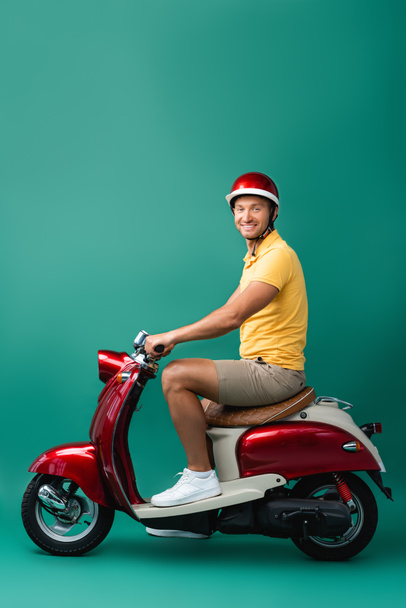 happy delivery man in helmet riding motorbike on blue - Foto, Imagem