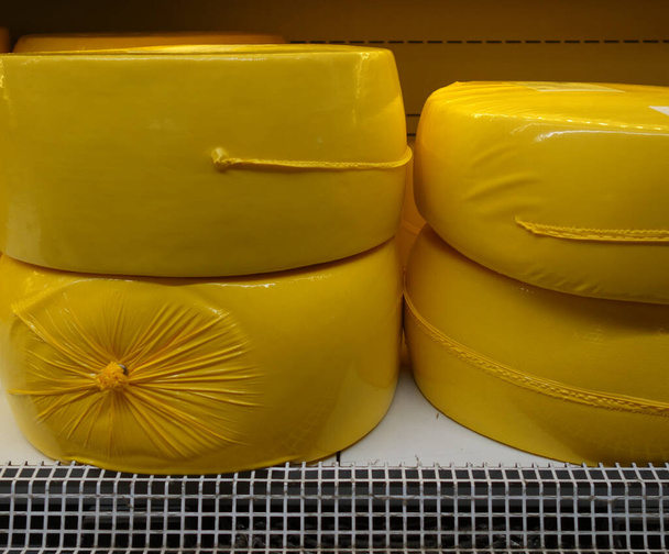 на полке в магазине колесо сыра в желтой упаковке. шаблон упаковки. копировальное пространство, макет. - Фото, изображение