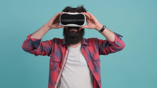 Bärtiger Mann mit Virtual-Reality-Brille. Studioaufnahme, türkisfarbener Hintergrund. - Filmmaterial, Video