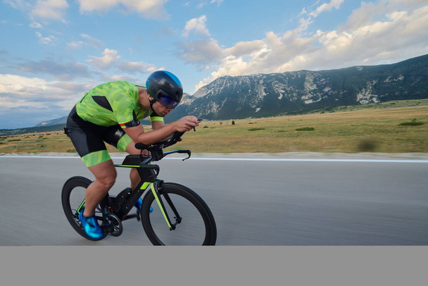 triathlon athlete riding professional racing bike at workout on curvy country road - Foto, Imagem