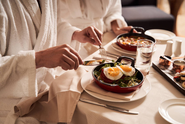 Two people in bathrobes eating at the table in hotel - Foto, Imagen