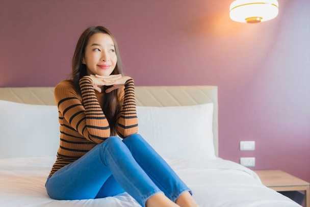 Портрет красива молода азіатка посміхається розслабитися на ліжку в інтер'єрі спальні
 - Фото, зображення