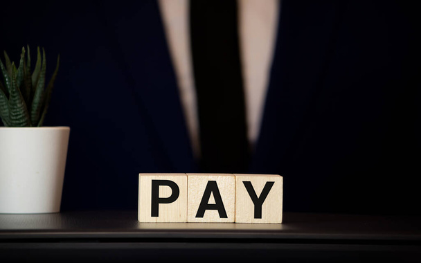 Wooden blocks with the word Payroll, money and a forklift. Payroll is the sum total of all compensation a business must pay to its employees for a set period of time or on a given date. Taxes. - Photo, Image
