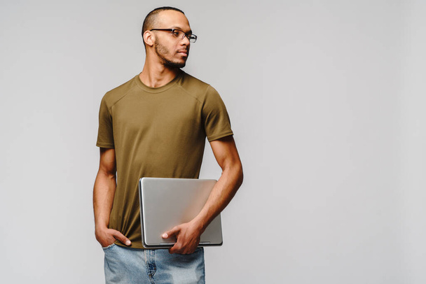A young african american man wearing glasses holding laptop pc - Foto, Imagem