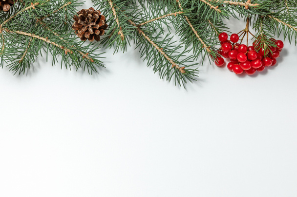 Natale e Capodanno composizione vacanza. Rami di abete, coni e bacche di viburno rosso su sfondo bianco. copia spazio.  - Foto, immagini