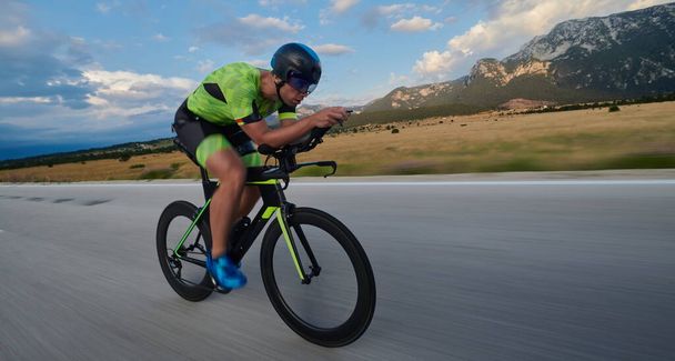 triathlon athlete riding professional racing bike at workout on curvy country road - Photo, Image