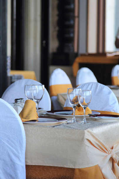 Πολυτελές εστιατόριο σε κλασικό στυλ με λευκό και κίτρινο τραπεζομάντηλο - Φωτογραφία, εικόνα