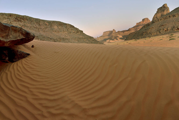 SAHARA DESERT IN ALGERIA IN TADRART NATIONAL PARK. SAND DUNES DESERT LANDSCAPE AND ROCK FORMATIONS - Photo, Image