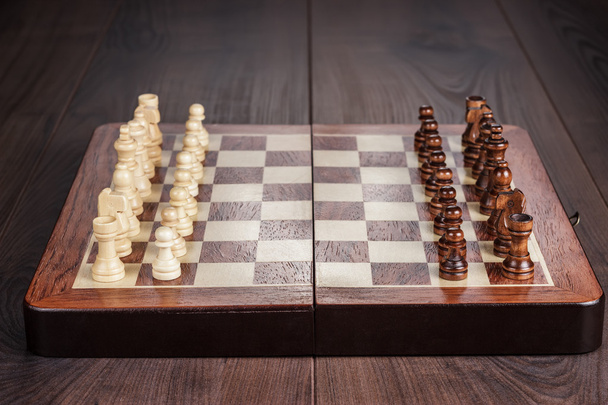 Chess board with figures on wooden table - 写真・画像