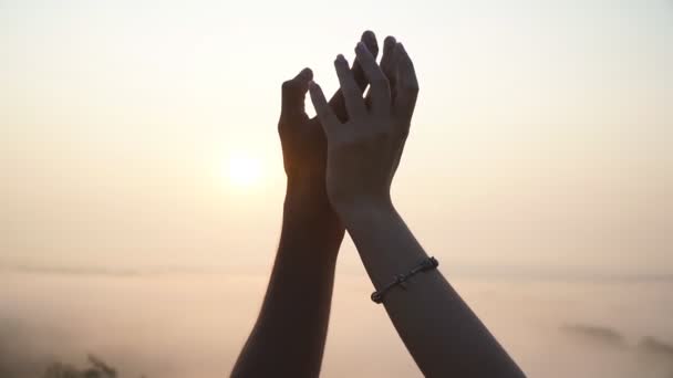 Silhouet van mannelijke en vrouwelijke handen die elkaar vasthouden bij zonsondergang. Jong stel sluit zich buiten aan. Concept van liefde en geluk. Geliefden paar genieten van prachtig romantisch moment - Video