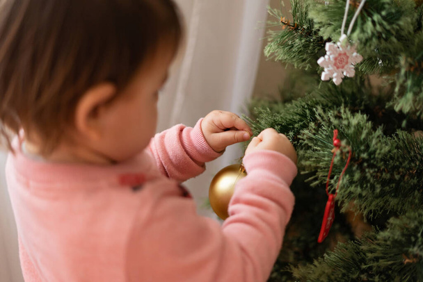 Toddler girl decorating christmas tree at home. December traditions for kids. - Zdjęcie, obraz