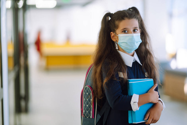 Colegiala en máscara médica protectora en corredor escolar al regresar a la escuela durante la cuarentena COVID-19. - Foto, Imagen