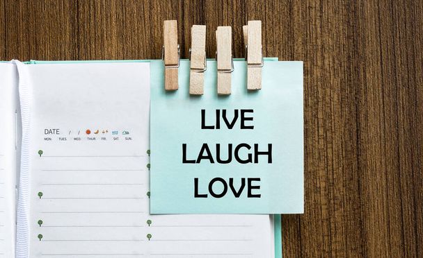 Live lachen liefde notities papier en een wasknijpers op houten achtergrond - Foto, afbeelding