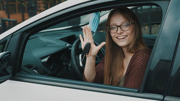 Boldog arckifejezése fiatal kaukázusi nő ül a vezetőülésen, és integetett autókulcsokkal - Fotó, kép