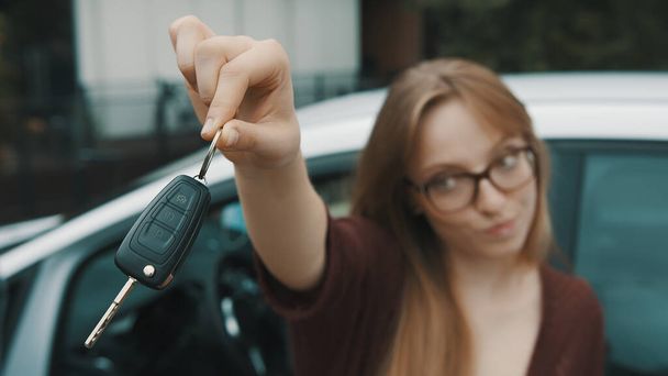 Giovane donna caucasica felice di fronte alla nuova auto e con le chiavi in mano - Foto, immagini