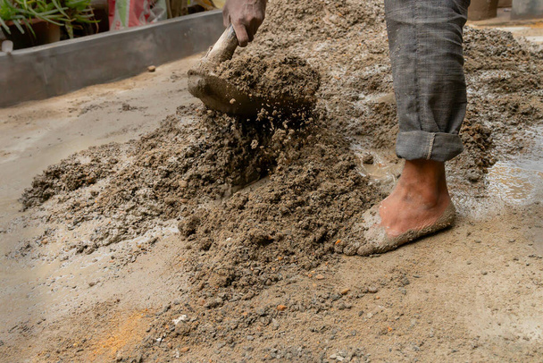 Колката, Західна Бенгал, Індія - 6 січня 2020: індійська робоча суміш цементу і води вручну на підлозі за допомогою лопати. Stcok image. - Фото, зображення