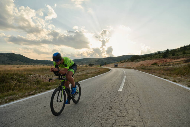 triathlon athlete riding professional racing bike at workout on curvy country road - Zdjęcie, obraz