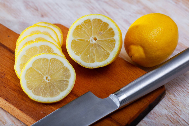 Lemon and knife on cutting board - Фото, зображення