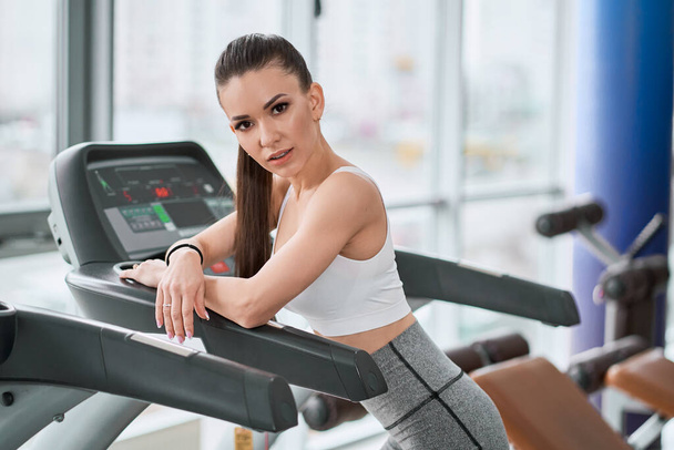 Portrait of a beautiful and fit woman stading on a treadmill - Valokuva, kuva