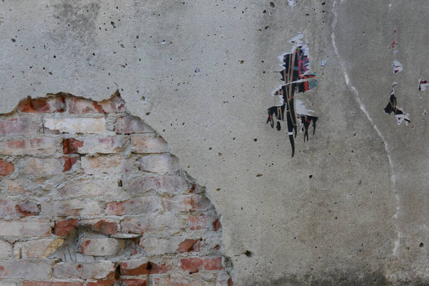 weerbestendige muur met overblijfselen van een poster en gedeeltelijk verwijderd stucwerk, die de onderliggende bakstenen blootlegt, Lissabon, Portugal - Foto, afbeelding