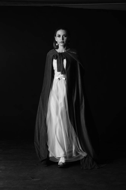 όμορφη γυναίκα σε μανδύα σε σκούρο φόντο, Δραματική και φανταστική γυρίσματα  - Φωτογραφία, εικόνα