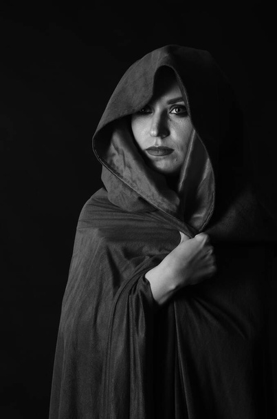 beautiful woman in cloak on dark background, Dramatic and fantastic shooting  - Фото, изображение