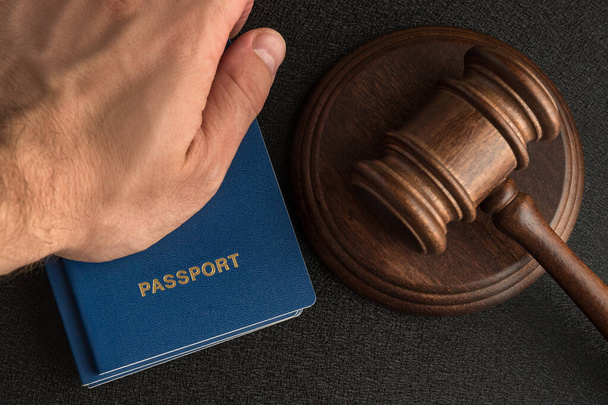 Чоловіча рука тримає паспорт поруч з дерев'яним даром. Отримати громадянство. Юридична імміграція
 - Фото, зображення