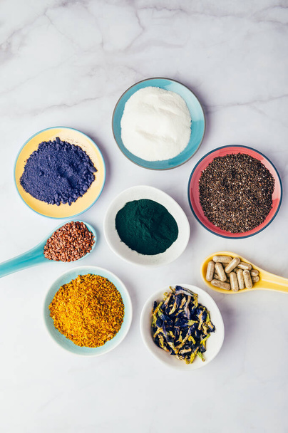 Variety of healthy food supplements such as blue matcha, butterfly pea flowers, collagen powder, spirulina powder, vitamins for vegans and vegetarians, flax and chia seeds, - Photo, Image
