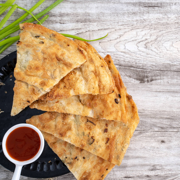 Taiwanese food - delicious flaky scallion pie pancakes on bright wooden table background, traditional snack in Taiwan, top view. - Фото, изображение