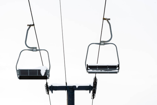 při pohledu na prázdné lyžařské sedačkové lanovky pokryté sněhem na bílém pozadí.  - Fotografie, Obrázek