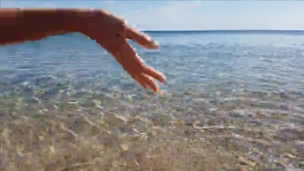 Primer plano de la mano femenina tocando el agua de mar - Imágenes, Vídeo