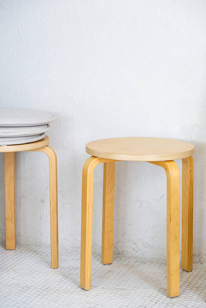 Drewniany stołek w minimalnym stylu przy białej ścianie małej kawiarni kawowej. - Zdjęcie, obraz