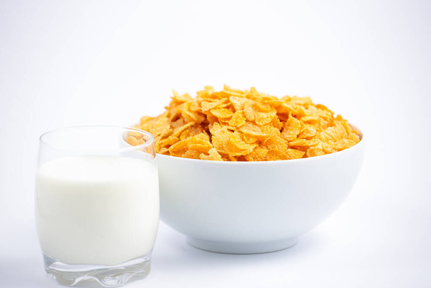 El cereal natural de maíz en escamas en tazas y leche es un desayuno saludable que es bueno para su cuerpo todos los días sobre un fondo blanco.. - Foto, Imagen