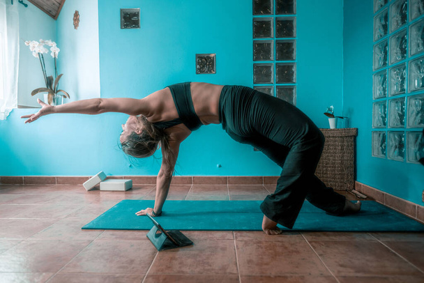 Joven rubia latina enseñando yoga en una clase virtual en casa con fondos azules - Foto, imagen