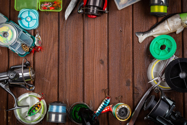 Varie tacche di pesca con esche e bobine su sfondo marrone in legno con posto per il testo. Progettazione per pubblicità ed editoria. - Foto, immagini