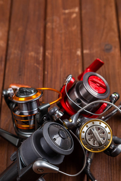Different fishing tacles with lures and reels on wooden brown background with place for text. Design for advertisment and publishing. - Photo, Image