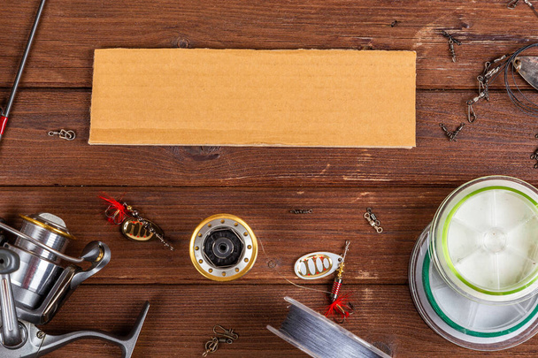 Διαφορετικές tacles αλιείας με θέλγητρα και κυλίνδρους σε ξύλινο καφέ φόντο με θέση για κείμενο. Σχεδιασμός διαφημίσεων και εκδόσεων. - Φωτογραφία, εικόνα